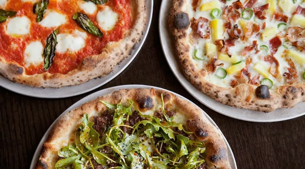 Three Neapolitan pizzas: Margherita, pineapple-bacon, and arugula.