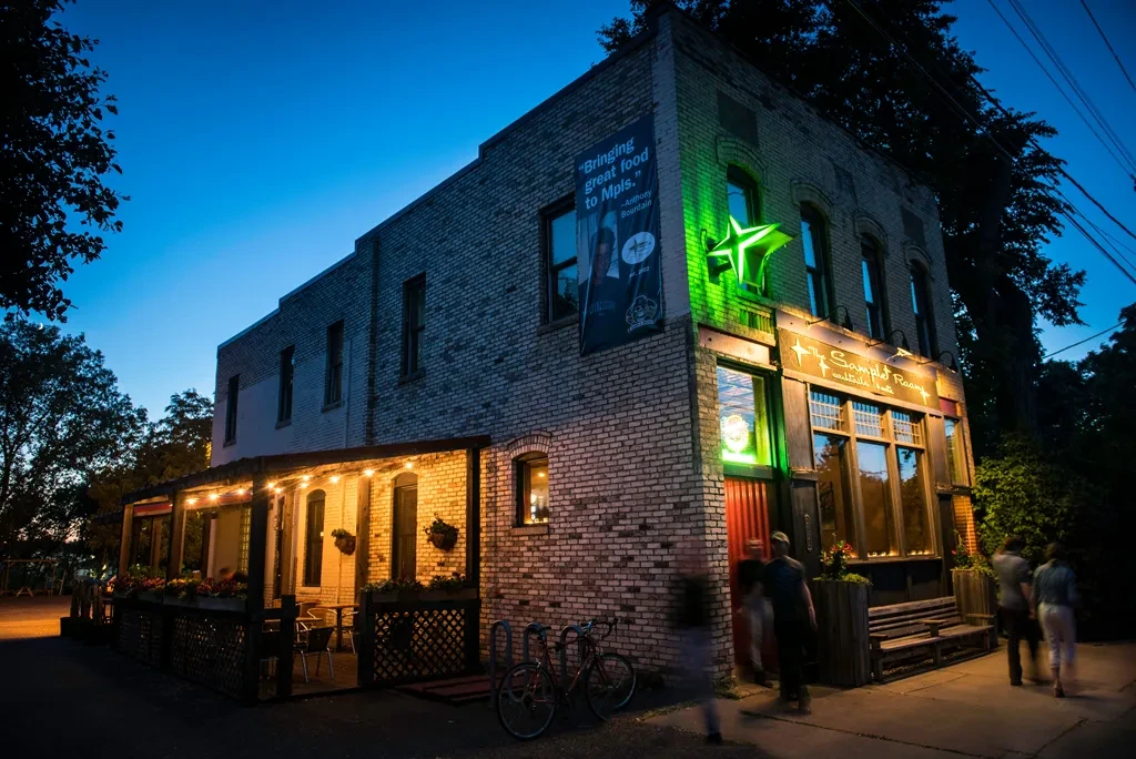 Brick Sample Room restaurant at dusk with green neon and outdoor patio.