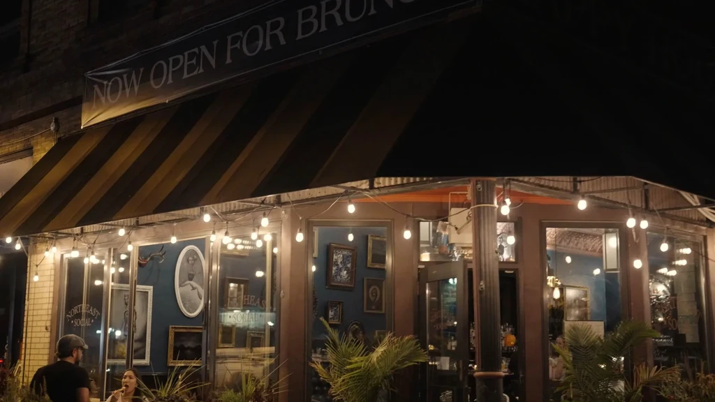 Night shot of restaurant with black-yellow awning and "NOW OPEN FOR BRUNCH."