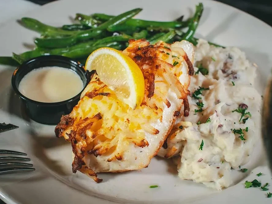 Crispy potato-crusted fish with mashed potatoes, sauce, and green beans.