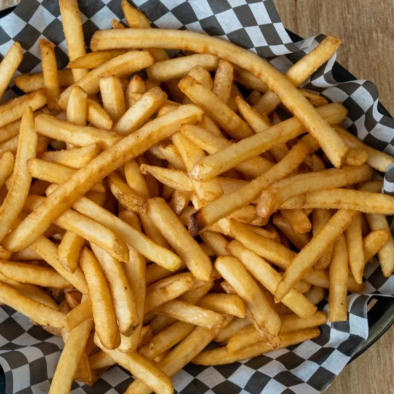 Top-down view of golden-brown french fries in a checkered paper-lined basket.