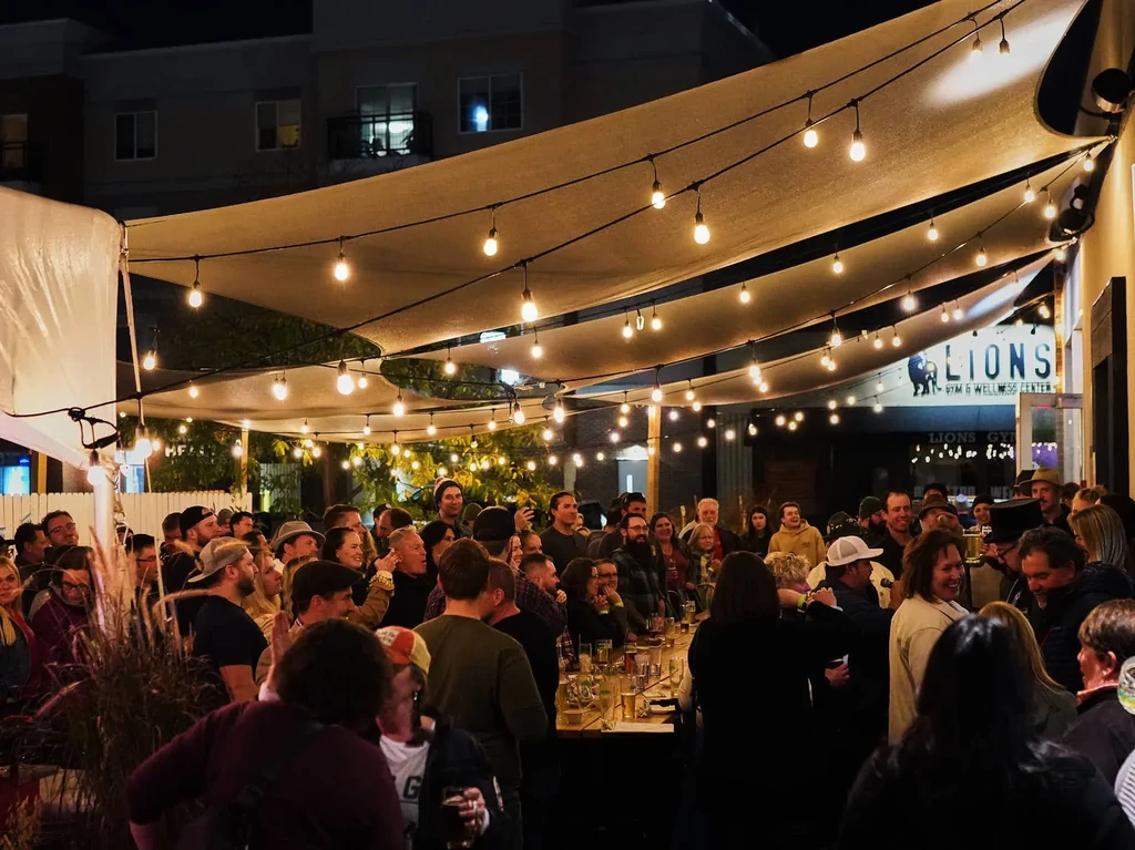 Busy urban patio at night, illuminated by string lights.