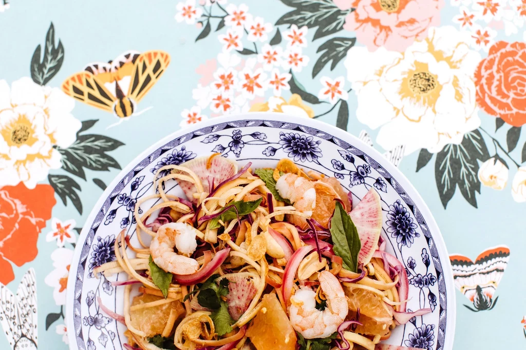 Vibrant salad with shrimp, pomelo, and greens in a patterned bowl.