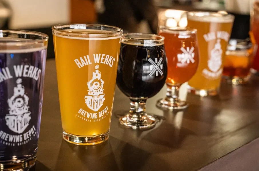 Close-up: Four branded beers and stout lined on a dark bar.