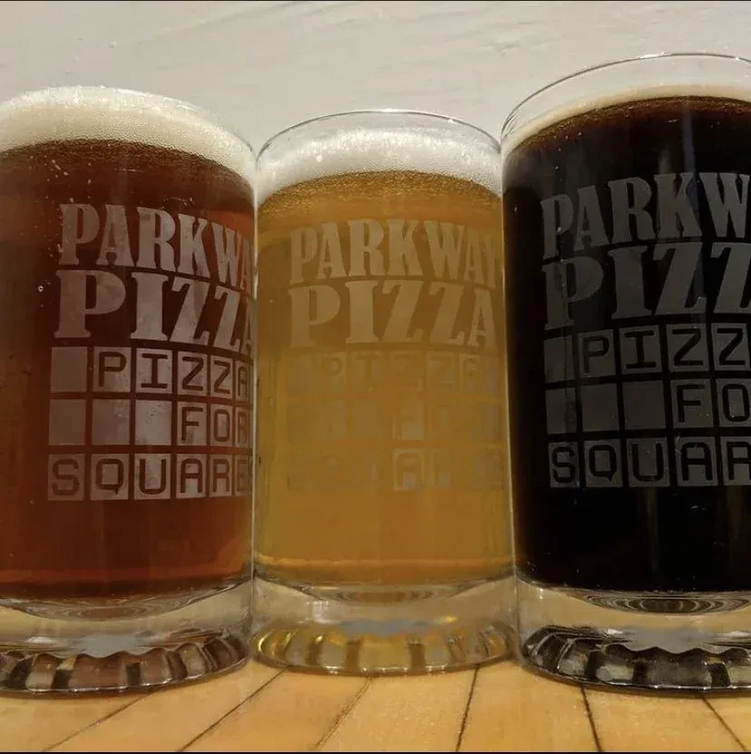Three distinct beers in etched Parkway Pizza glasses.
