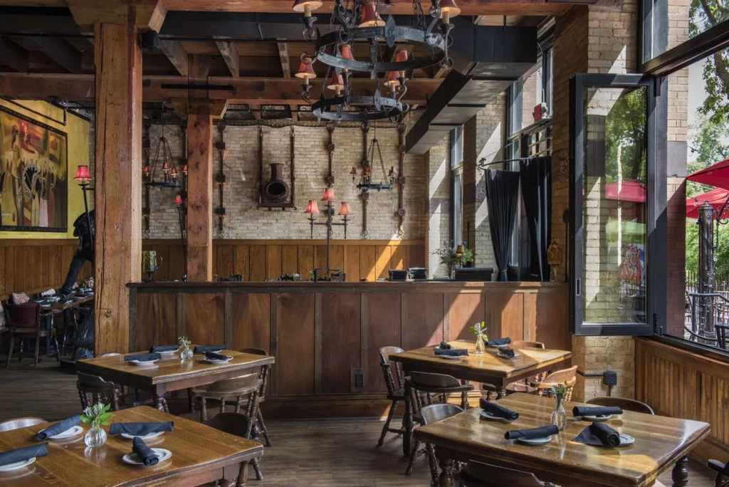 Rustic restaurant interior with wooden tables, exposed brick, and ornate lighting.