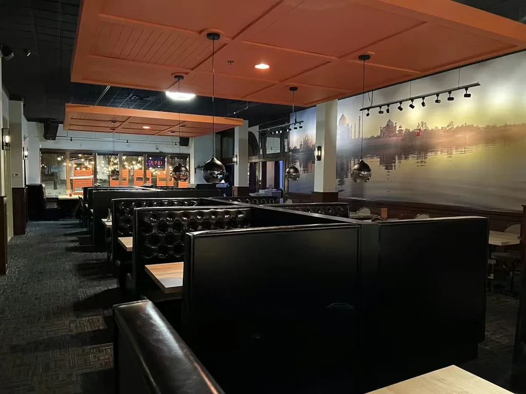 Modern restaurant interior with dark booths and Taj Mahal mural.