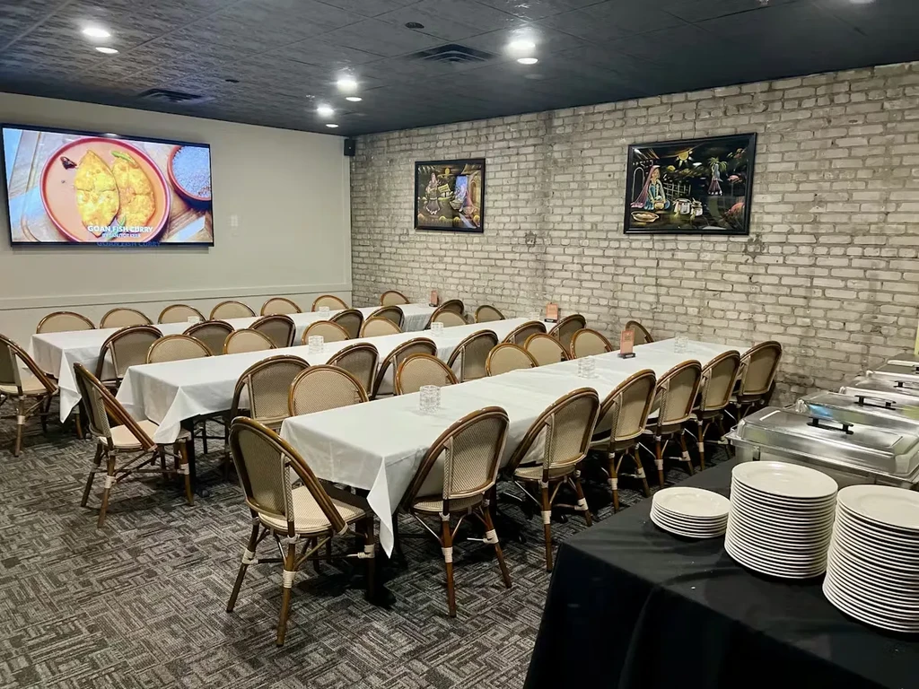 Spacious dining hall with arranged tables, chairs, buffet, and food display.