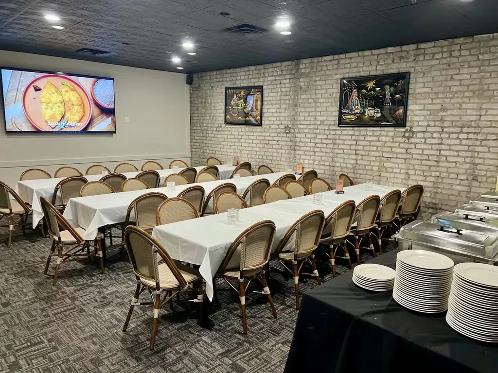 Event-ready restaurant dining area with buffet, rattan chairs, and curry on TV.