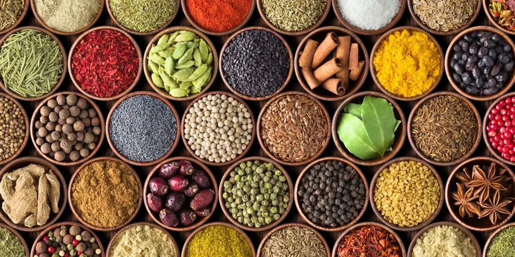 Numerous wooden bowls filled with a mosaic of diverse spices and herbs.