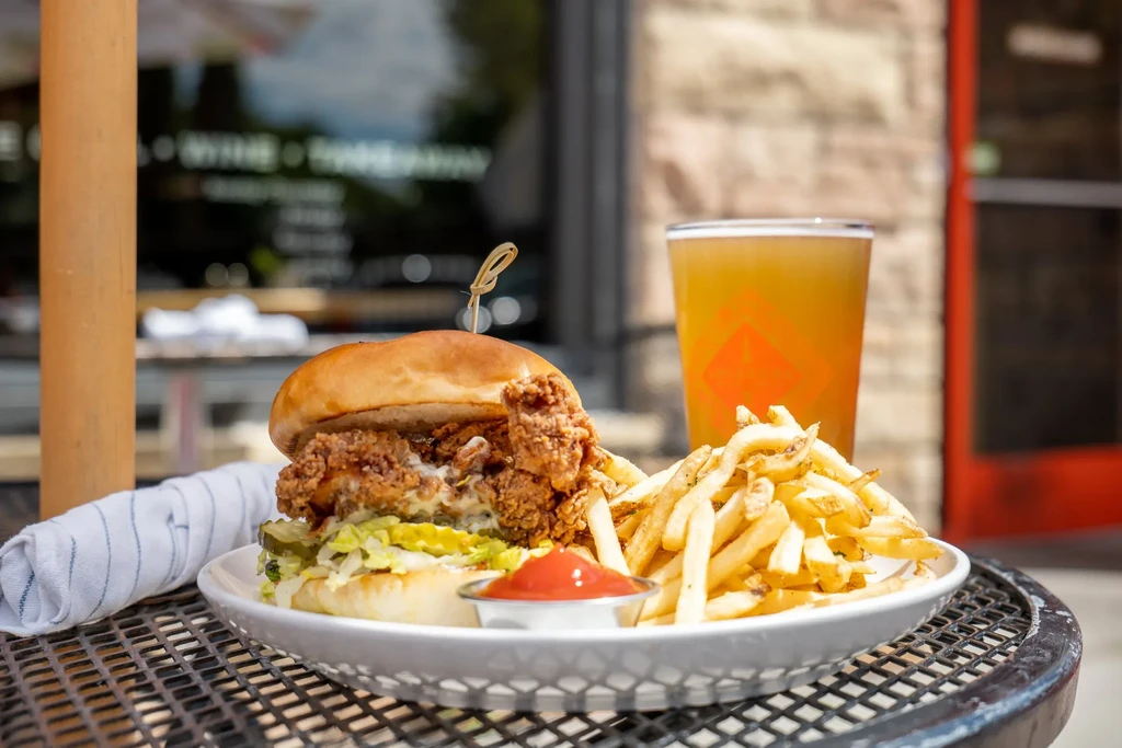 Crispy fried chicken sandwich with fries and ketchup on an outdoor table.