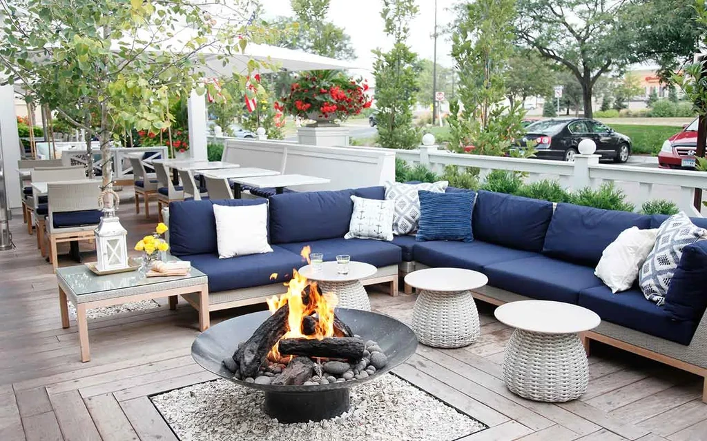 Outdoor restaurant patio with navy sectional and crackling fire pit.