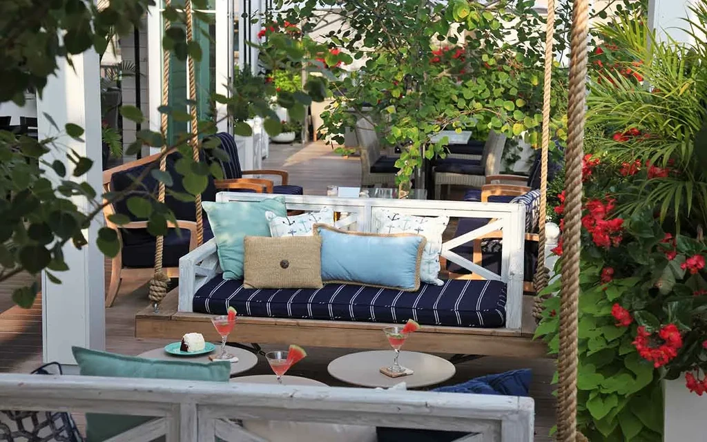 Outdoor dining lounge with swing bench, cocktails, and cake.