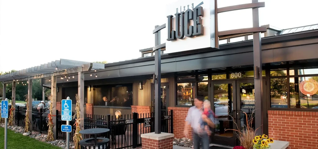 Modern Pizza Luce restaurant exterior with lit patio and fall decor.