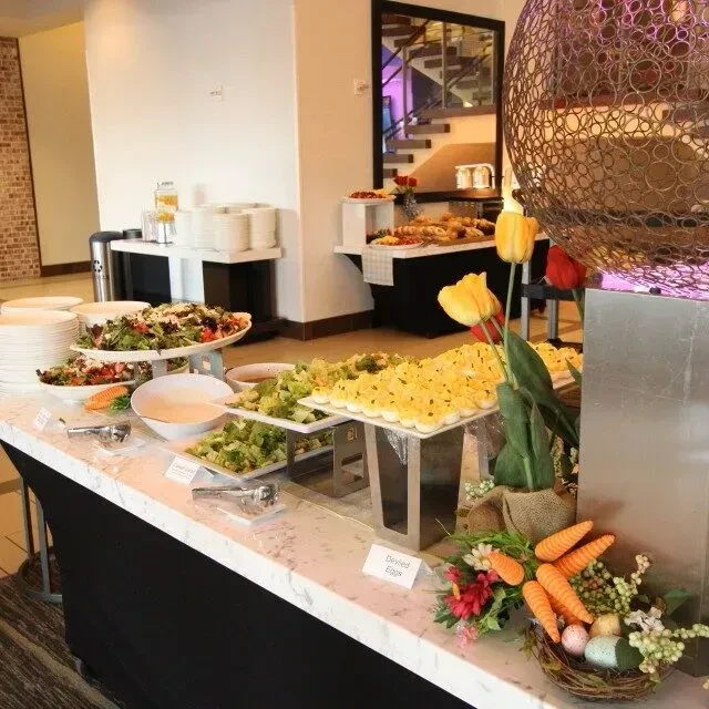 Brightly lit buffet counter with salads, deviled eggs, and spring decor.
