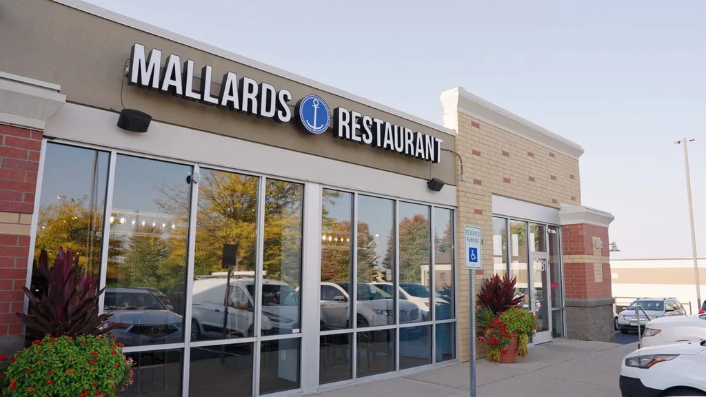 Modern Mallards Restaurant exterior, reflective windows show autumn trees and cars.
