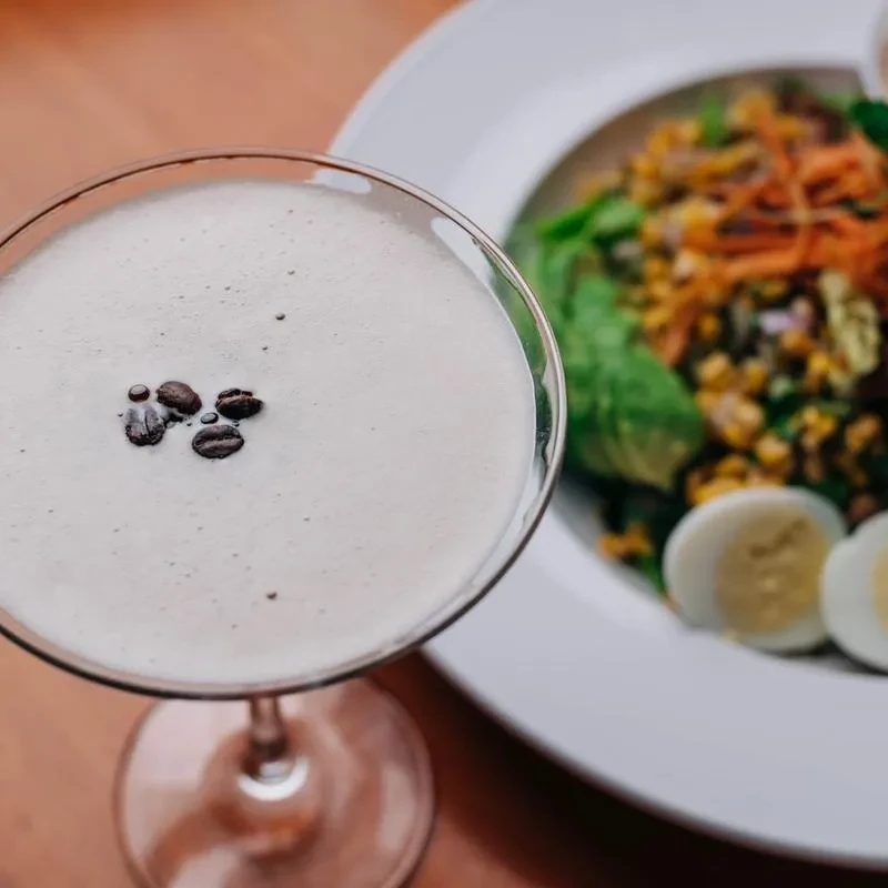 Creamy beverage in martini glass, garnished with three coffee beans.