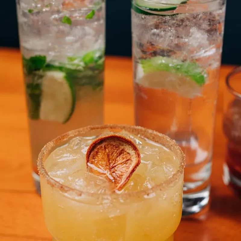 Three distinct garnished cocktails on a wooden surface.