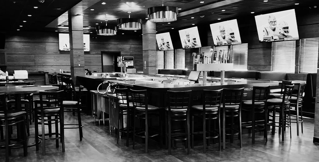 Empty black and white sports bar with multiple TVs displaying football.