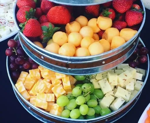 Multi-tiered serving tray with fresh fruits and assorted cheeses.