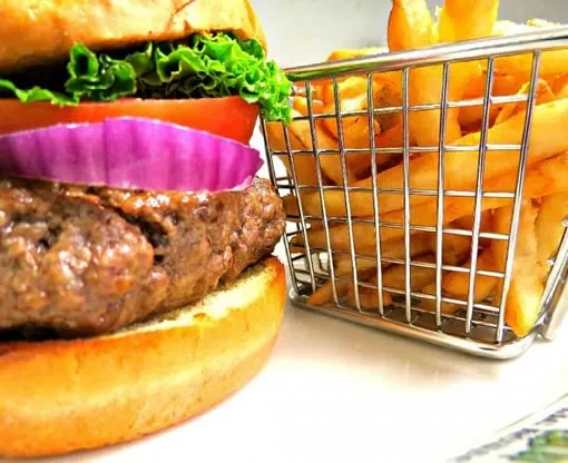 Classic burger with red onion, tomato, lettuce, and golden french fries.