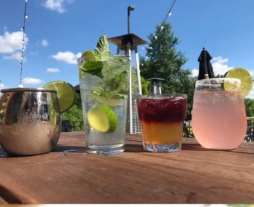 Four distinct beverages on a sunny outdoor wooden table.