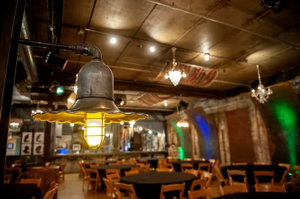 Industrial-chic venue interior with vintage lamp, exposed ceiling, and event tables.