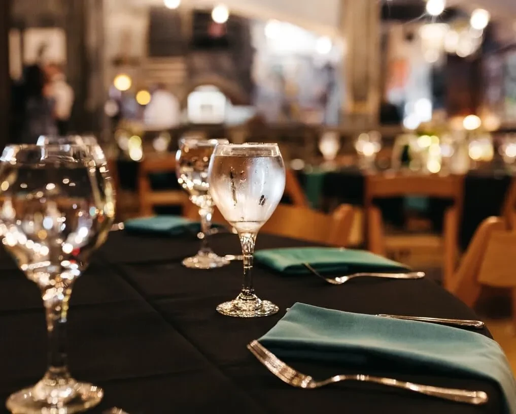 Elegant restaurant table setting with three cold water glasses and teal napkins.