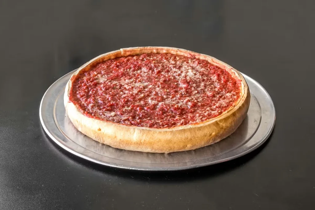Deep-dish pizza with golden crust, chunky tomato sauce, and grated cheese.