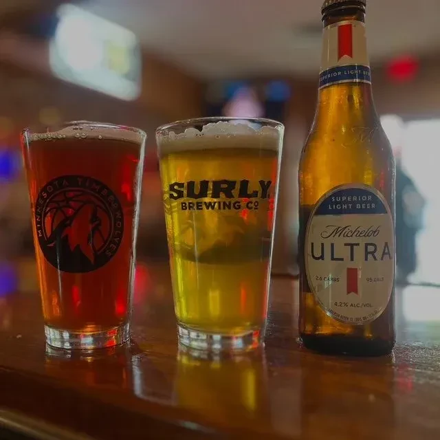 Three beers: Minnesota Timberwolves, Surly, and Michelob Ultra on a bar.