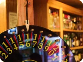 Black spinner wheel with numbers and pointer hangs in a bar.