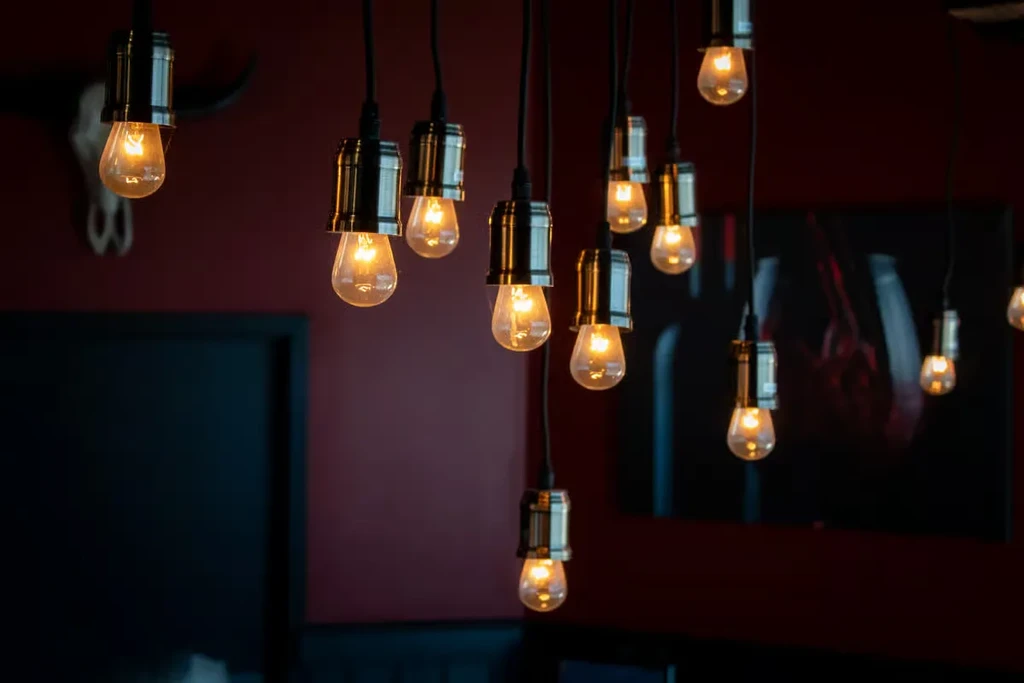 Warm-glowing vintage Edison bulbs in dark fixtures against a rustic wall.