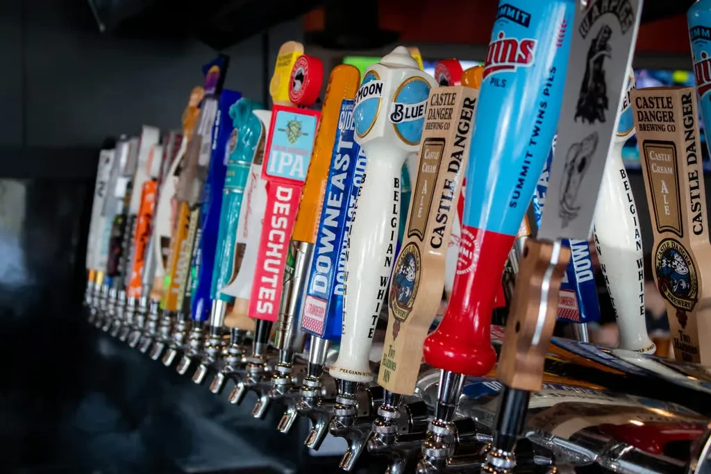 A long row of colorful beer tap handles at a bar.