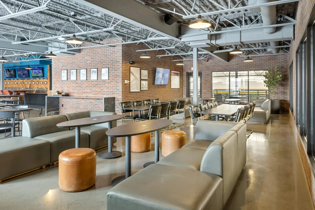 Modern industrial-chic restaurant interior with sofas, dining tables, and bar.