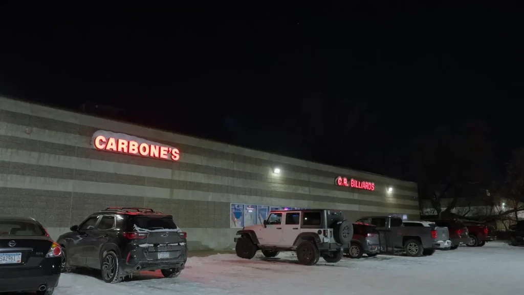 Nighttime shot of Carbone's and C.R. Billiards signs above snowy parking.