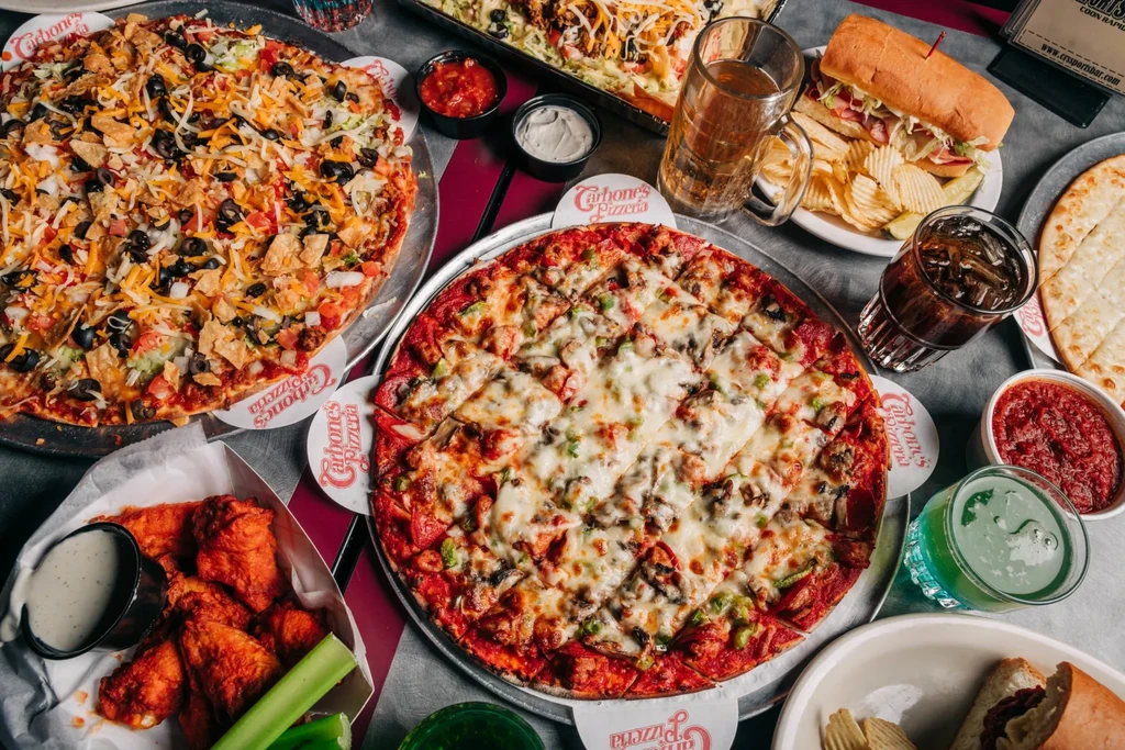 Carbone's Pizzeria table with pizzas, wings, sub, and drinks.