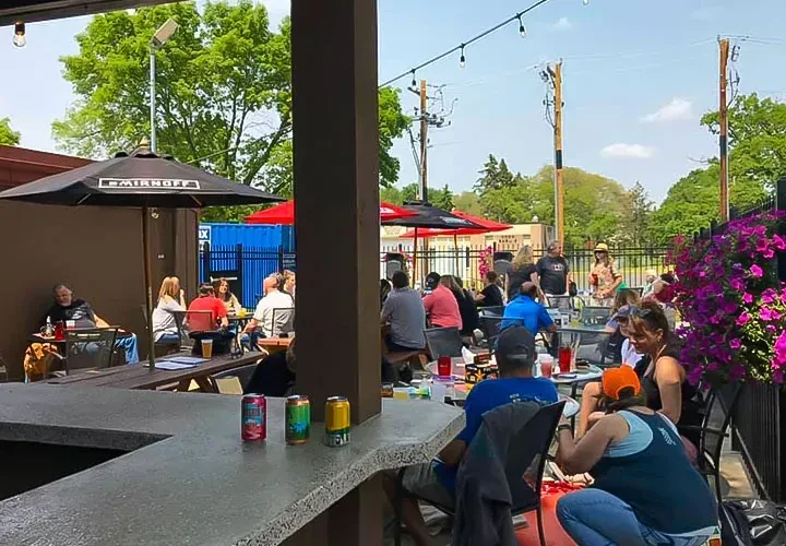 Outdoor restaurant patio with patrons, colorful drinks, Smirnoff umbrella.