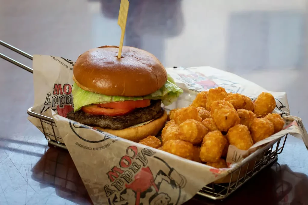 Burger and tater tots in a 'Muddy Cow' branded wire basket.