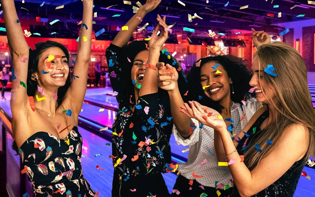 Four women celebrate amidst colorful falling confetti.
