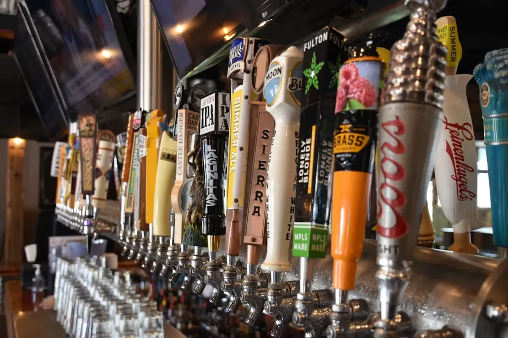 Many branded beer tap handles in a row at a bar.