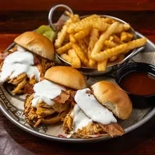 Three sliders with sauce and bacon, crinkle fries, and dipping sauce.