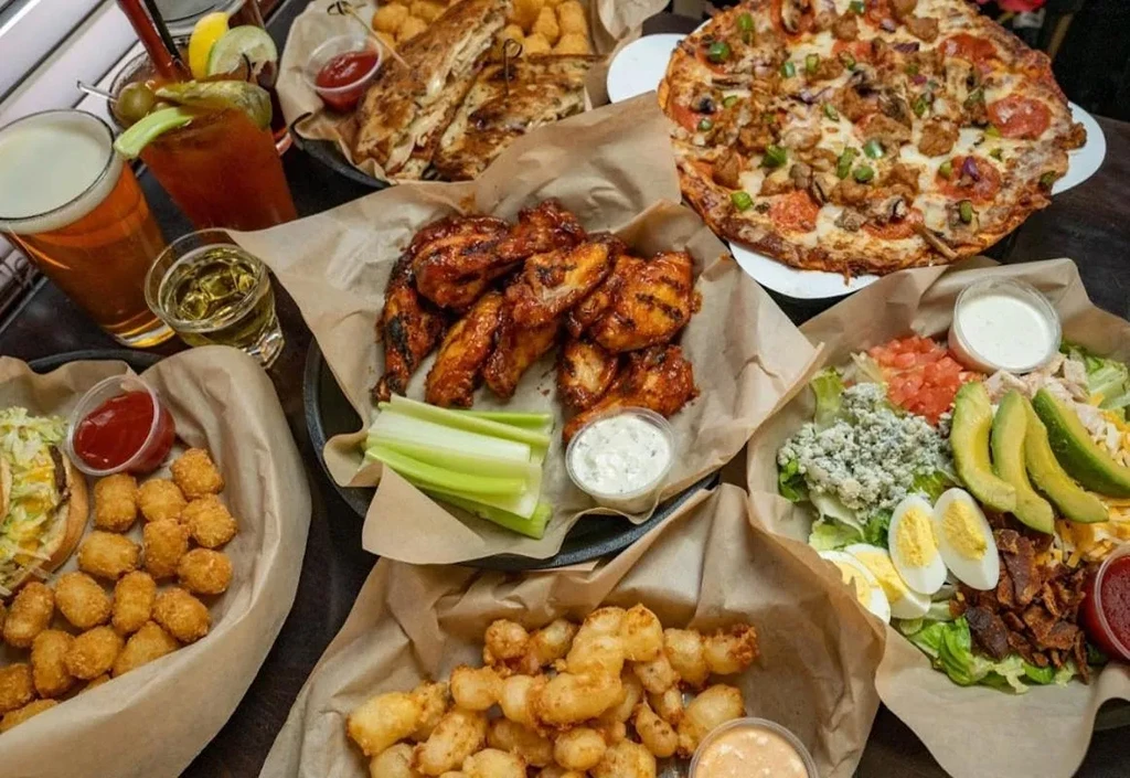 Overhead shot of pizza, wings, salad, tater tots, and drinks.
