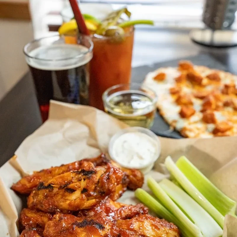 Table with chicken wings, celery, dipping sauce, and drinks.
