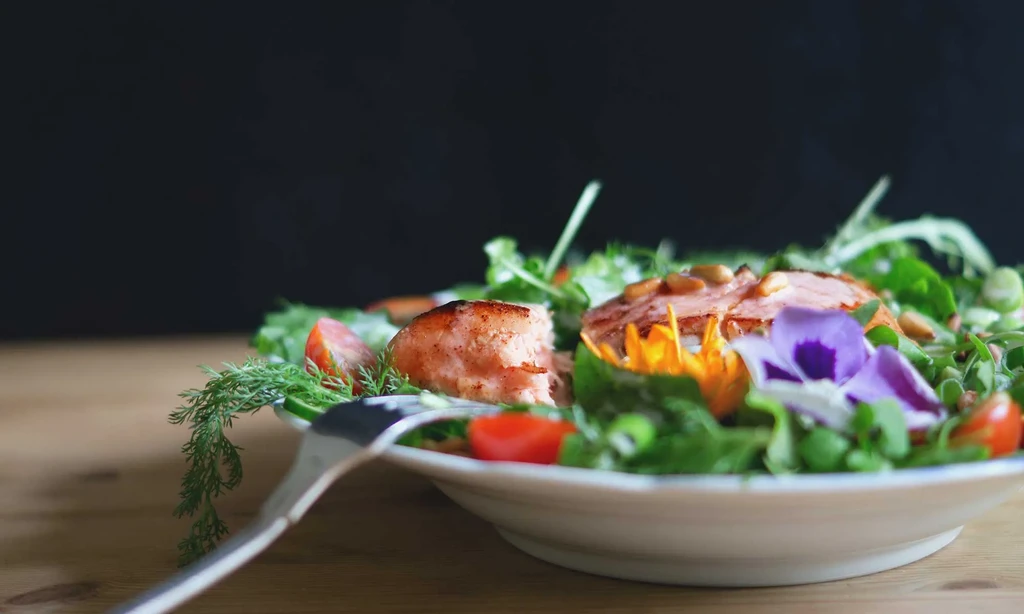 Grilled salmon salad with mixed greens, cherry tomatoes, and edible flowers.