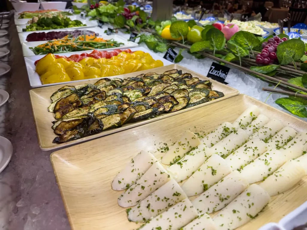 Vibrant buffet of fresh zucchini, peppers, carrots, and other cool salads.