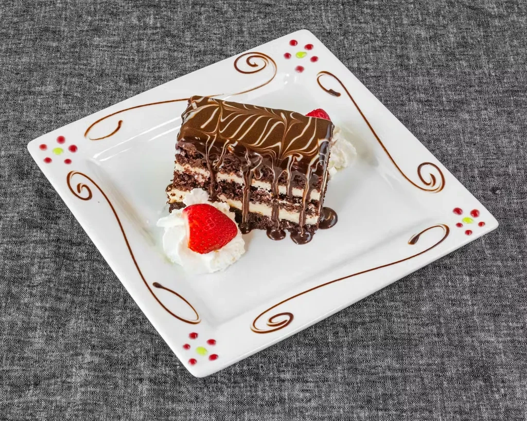Layered chocolate cake slice with ganache, whipped cream, strawberry.
