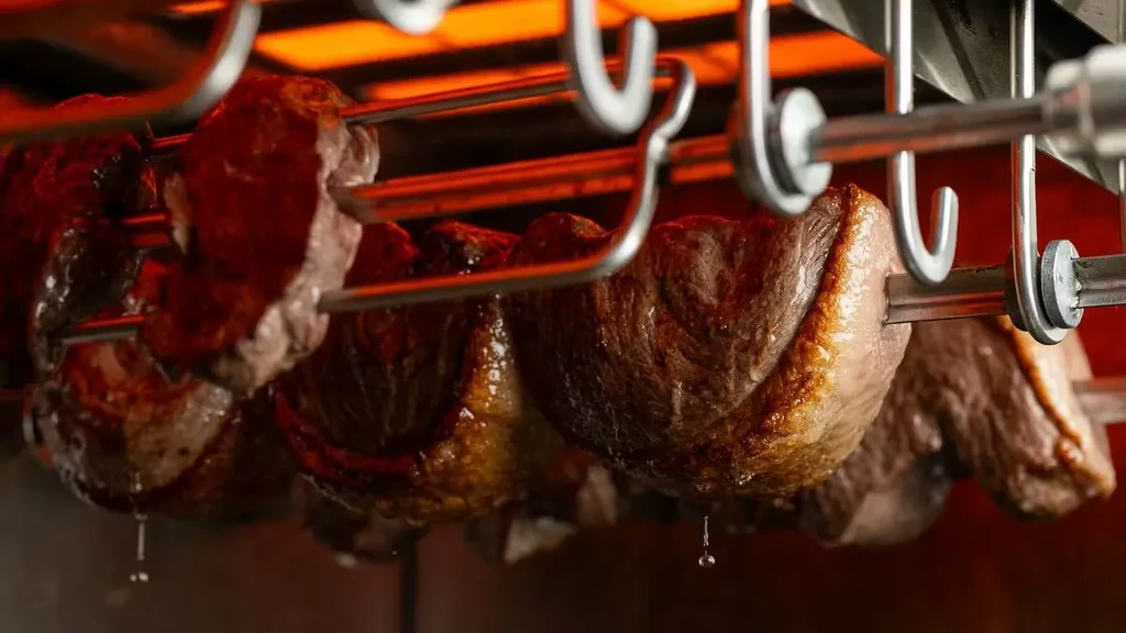 Skewered beef rotating in a glowing rotisserie, juices dripping.