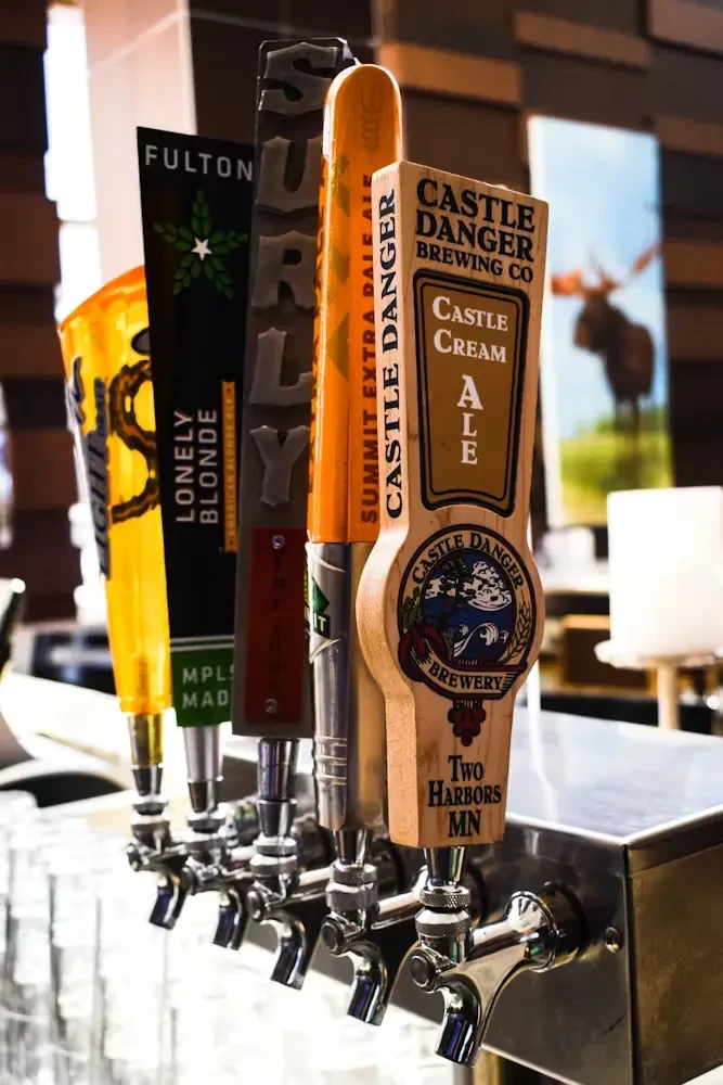 Four distinct beer tap handles lined up at a bar.