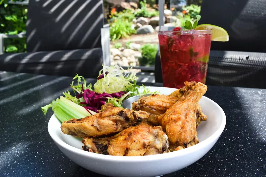 Chicken wings, salad, and red drink on an outdoor patio.