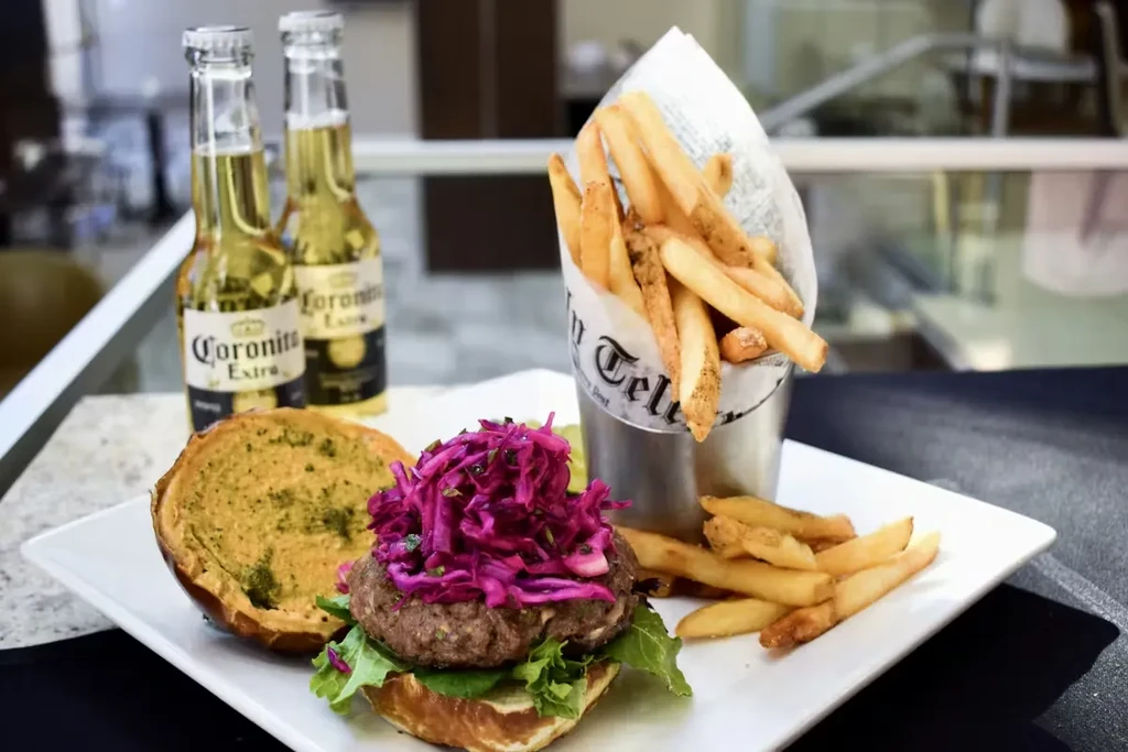 Gourmet burger, fries, and two Coronita Extra beers on a plate.